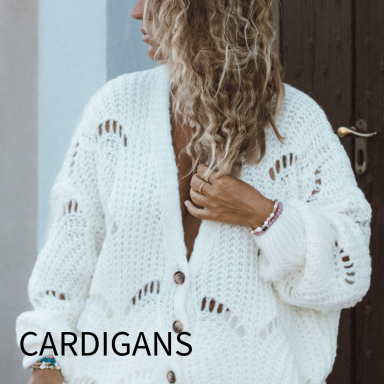 Frau mit lockigen Haaren trägt einen weißen, offenen Strickcardigan mit Knöpfen.